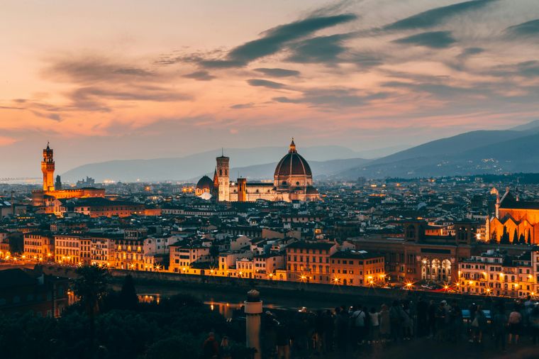 Panoramic sunset view of Florence, Italy, with the illuminated Duomo and city lights againts the backdrop of rolling hills